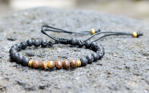 BRACCIALE CON PIETRE OCCHIO DI TIGRE SATINATO 6 MM E PIETRA LAVICA, CHIUSURA MACRAME REGOLABILE E PERLE IN METALLO GOLD PLATED